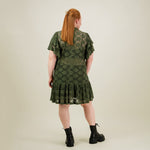 malli takaa päin jolla yllään naisten lyhyt vihreä pitsimekko frillahihoilla ja korkealla kauluksella, läpikuultava ilman aluspaitaa.