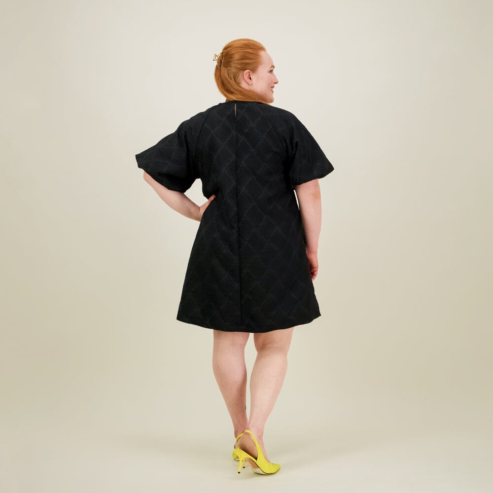 kuva takaa päin naisten lyhyt musta jacquard-mekko lyhyillä puhvihihoilla