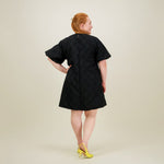 kuva takaa päin naisten lyhyt musta jacquard-mekko lyhyillä puhvihihoilla
