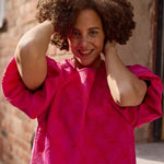 Lähikuva mallista jolla yllään naisten lyhyt jacquard-mekko oranssilla pohjalla ja pinkillä kuosilla, lyhyillä puhvihihoilla.