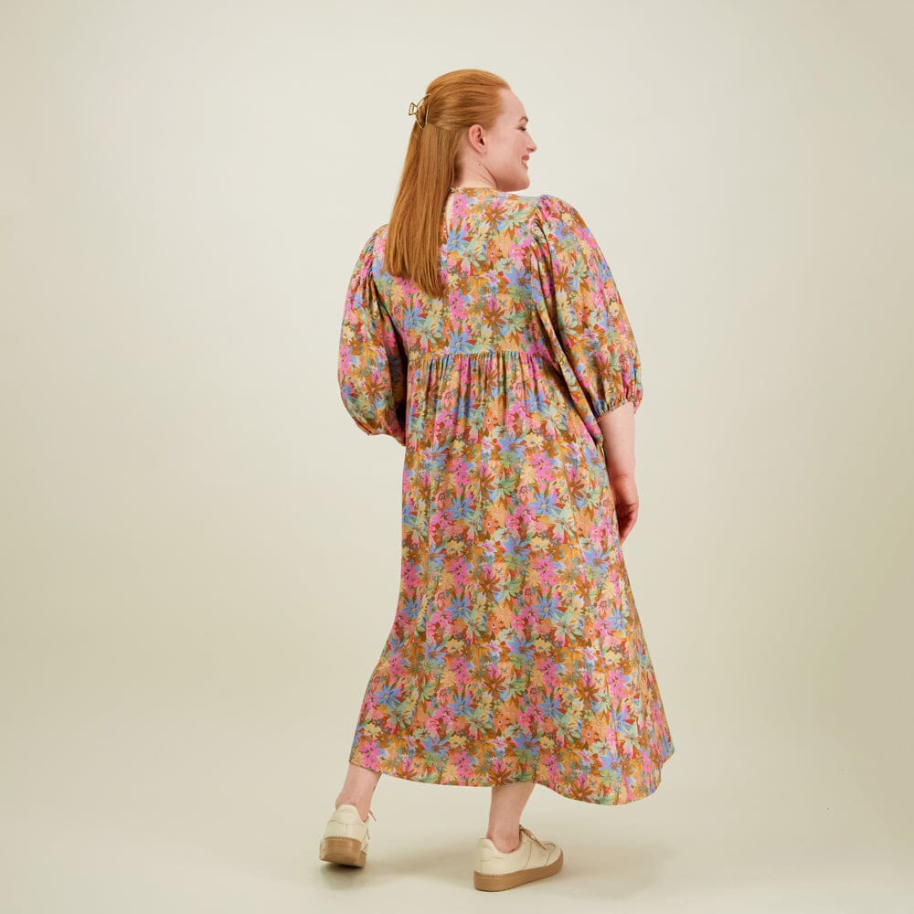 Kuva mallista takaa päin naisten midimittainen mekko puolipitkillä puhvihihoilla ja sivutaskuilla.