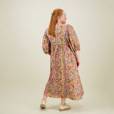 Kuva mallista takaa päin naisten midimittainen mekko puolipitkillä puhvihihoilla ja sivutaskuilla.