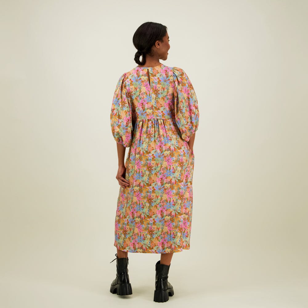 Kuva mallista takaapäin jossa naisten midimittainen mekko puolipitkillä puhvihihoilla ja sivutaskuilla.