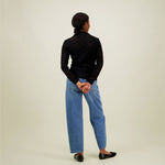 Naisten musta pitsipaita korkealla kauluksella ja pitkillä hihoilla, kuva mallista takaa päin. 