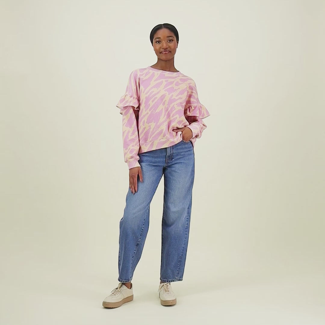 video jossa malli esittelee naisten oversize-mallinen purple-sävyinen collegepaita frillahihoilla ja graafisella kuosilla.