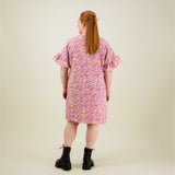 Naisten lyhyt suoralinjainen purple-sävyinen mekko kierrätyspolyesterista, frillahihoilla ja sivutaskuilla, kuva mallista takaa päin. 