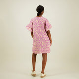 Naisten lyhyt suoralinjainen purple-sävyinen mekko kierrätyspolyesterista, frillahihoilla ja sivutaskuilla, kuva tummahiuksisesta mallista takaa päin. 