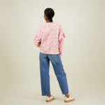 Naisten oversize-mallinen purple-sävyinen collegepaita frillahihoilla ja graafisella kuosilla, kuva takaa päin. 