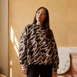 Naisten oversize-mallinen musta-beige collegepaita pehmeästä luomupuuvillasta, harjattu sisäpinta, lähikuva paidasta tummahiuksisen mallin päällä.