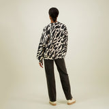 Naisten oversize-mallinen musta-beige collegepaita pehmeästä luomupuuvillasta, harjattu sisäpinta, kuva mallista takaa päin.