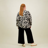 Naisten oversize-mallinen musta-beige collegepaita pehmeästä luomupuuvillasta, harjattu sisäpinta, kuva mallista takaa päin. 