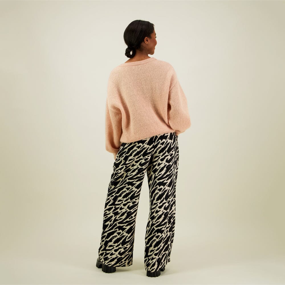 Naisten mustat suoralinjaiset housut kierrätyspolyesterista, reilunmittaisilla lahkeilla ja sivutaskuilla, kuva mallista takaa päin.