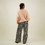 Naisten mustat suoralinjaiset housut kierrätyspolyesterista, reilunmittaisilla lahkeilla ja sivutaskuilla, kuva mallista takaa päin.