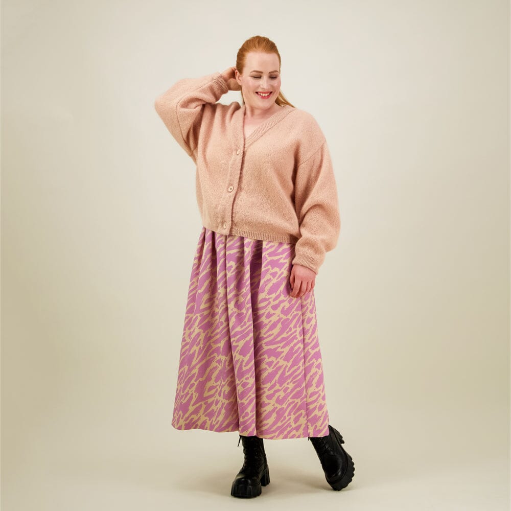 Naisten midimittainen purple-sävyinen laskostettu hame kierrätyspolyesterista, joustavalla vyötäröllä ja sivutaskuilla. Hame yhdistetty mohair-neuletakkiin. 