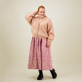 Naisten midimittainen purple-sävyinen laskostettu hame kierrätyspolyesterista, joustavalla vyötäröllä ja sivutaskuilla. Hame yhdistetty mohair-neuletakkiin. 