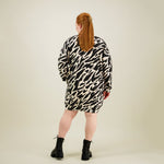 Naisten oversize-mallinen polvimittainen mustavalkoinen collegemekko sivutaskuilla, kuva takaa päin. 